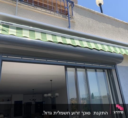 סוכך ירוק מפוספס מותקן מעל חלון זכוכית